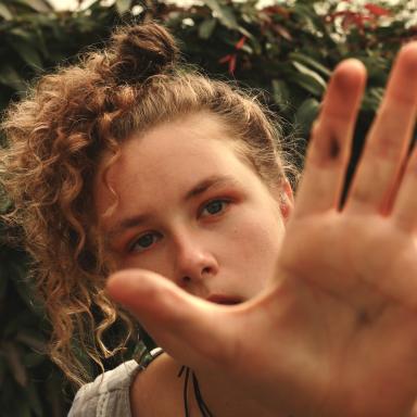 Image of Tara-Lily Klein. Her hand is in front of the camera, so you can see half of her face.