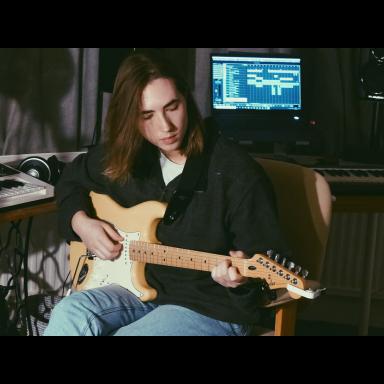 Jensyn sitting in a recording studio playing an electric guitar