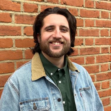 Man wearing denim jacket in front of brick wall