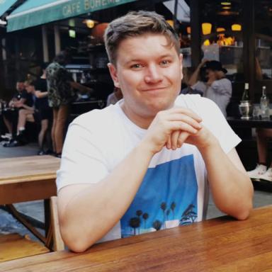 Iain mcgoldrick sits at a wooden table and holds his hands together