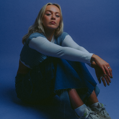 frankie wears a blue outfit and poses against a blue background