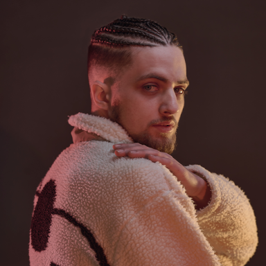 a man wears his hair in cane rows and looks over his shoulder