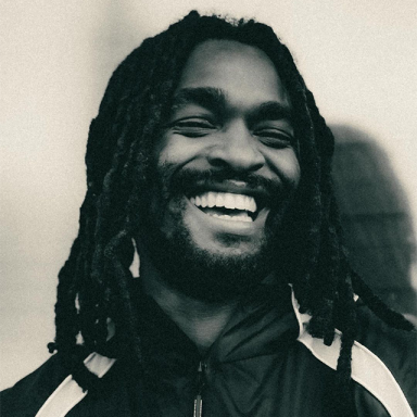 a man with dreadlocks laughs in a sepia tone photograph