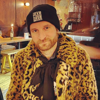 paul wears a leopard print coat and a black beanie