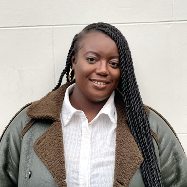 shanice wears her hair in braids, a white shirt and green coat